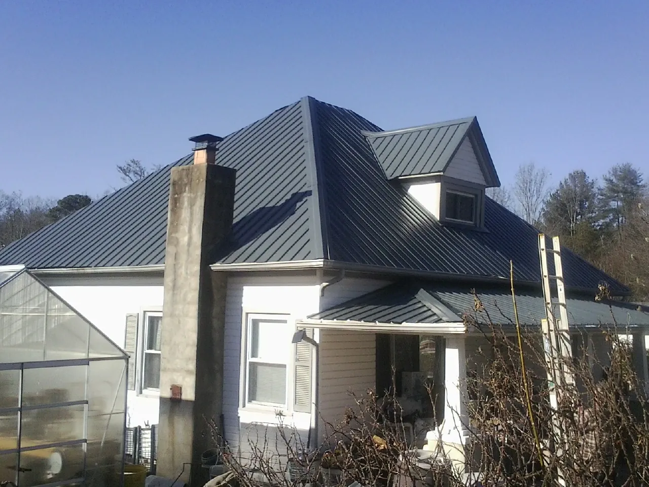 Dark blue standing seam metal roof on a white farmhouse with dormer — Slate & Tile Roof Repair by Roofing Brothers in Sutherlin
