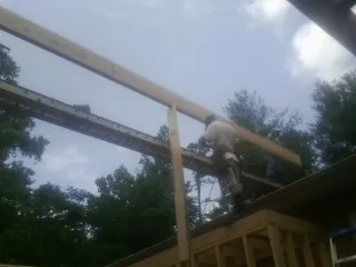 Carpenter setting a ridge beam over a new addition frame — Ice Dam Removal by Roofing Brothers in Sutherlin