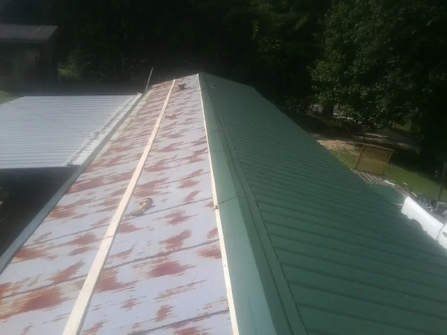 Old rusted panels beside newly installed green metal roofing — Wind Damage Roof Repair by Roofing Brothers in Sutherlin