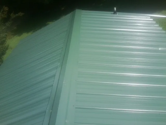 New green metal panels meeting at the ridge of a roof — Flat Roof Repair work by our crew in Sutherlin