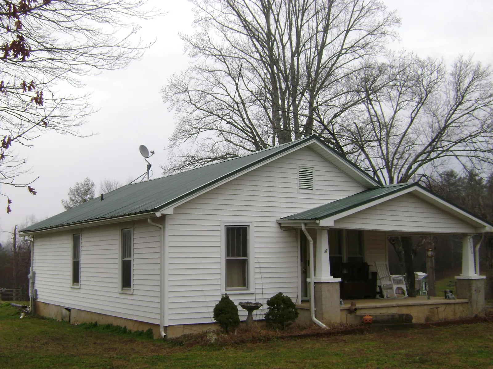 Green metal roof on a white bungalow with a side porch in Sutherlin