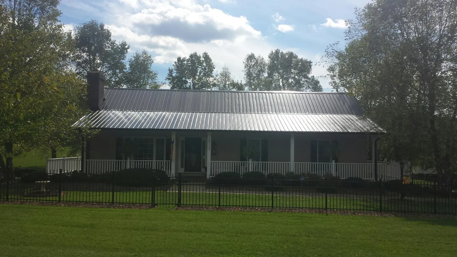 Gray metal roof on a brick ranch with a full width front porch — Gutter Guard Installation work by our crew in Sutherlin