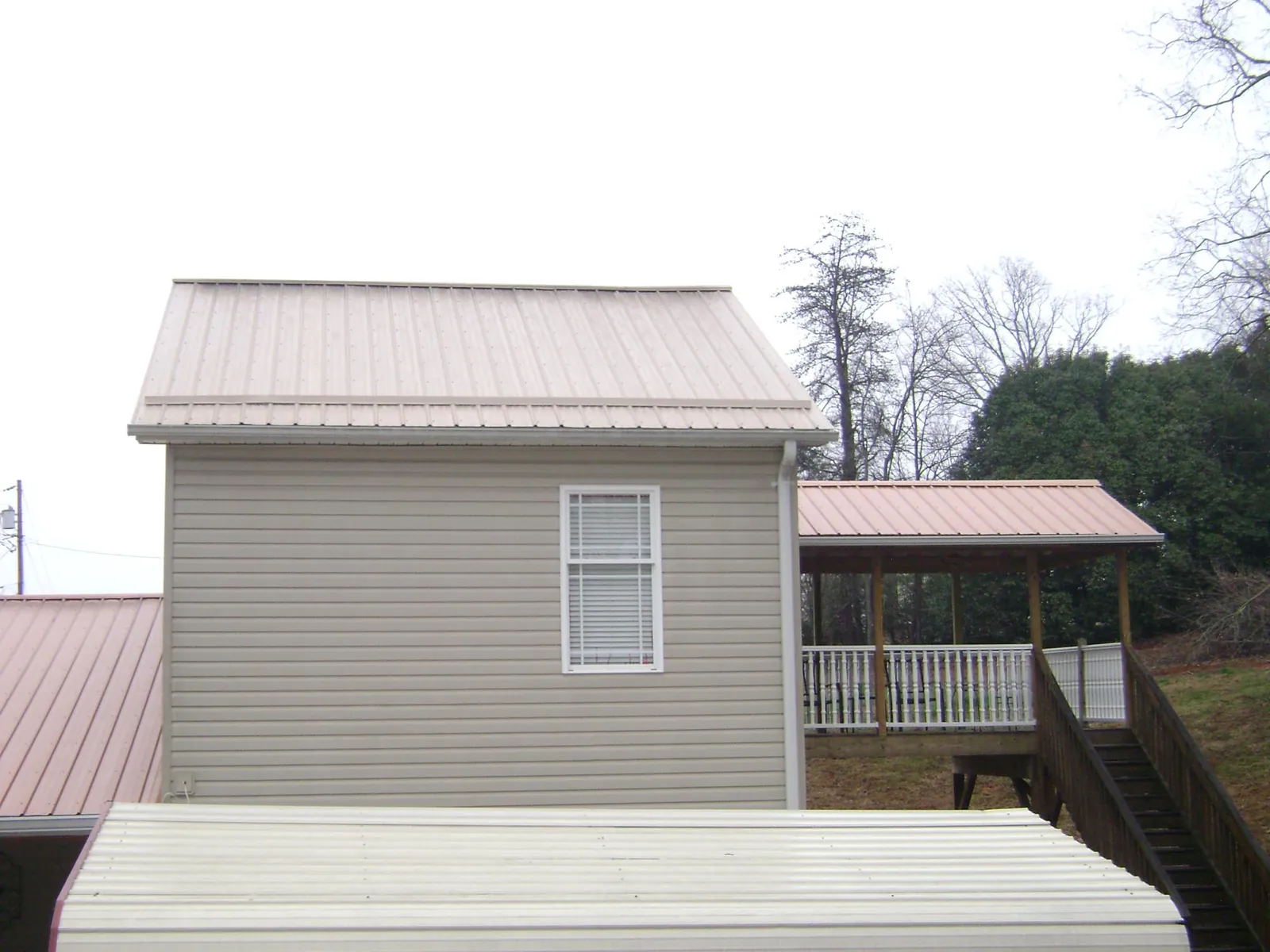 Tan metal roofs on a two story addition and attached porch, from a Roof Replacement job in Sutherlin