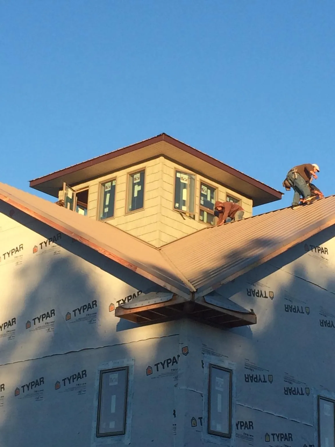 Roofers working around a rooftop cupola on a new metal roof at sunset — Roof Waterproofing in Sutherlin by Roofing Brothers